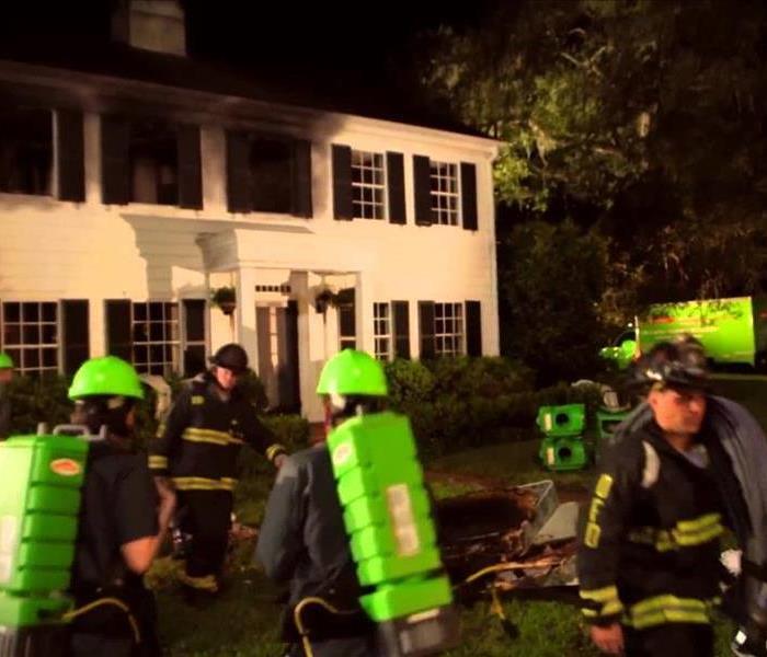 SERVPRO professionals and fire fighters outside a fire damaged home.